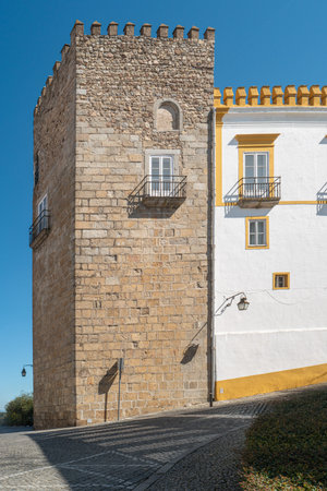 The view of narrow paved street of Evora with the cozy white and yellow houses. Evora. Alentejo....