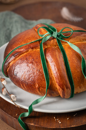 Portuguese traditional Easter cake Folar without eggs on easter table with a green velvet ribbon and...