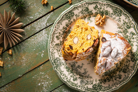 Portuguese Bolo Rainha slice: sugared nuts on festive bread, on a green table with Christmas ornaments. A traditional dessert for Christmas, New Year's & Epiphany. Top viewの写真素材