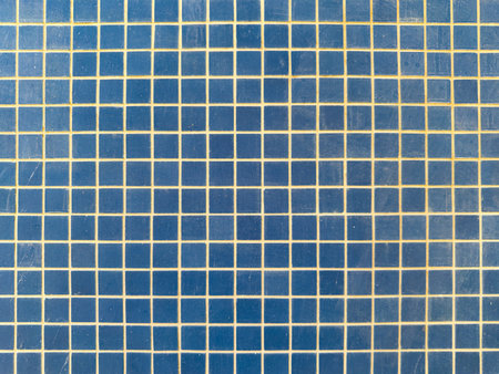 Close-up of a vibrant blue square tiled surface with thin, contrasting grout lines, creating a...