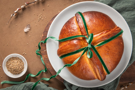 Portuguese traditional Easter cake Folar without eggs on easter table with a green velvet bow and a bowl of fennel seeds. Top viewの写真素材