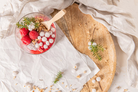 An overhead shot of a single glass of layered raspberry and chia seed pudding on a rustic wooden...