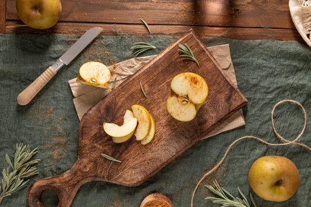 An overhead shot of a rustic still life with sliced russet apples sprinkled with cinnamon on a...