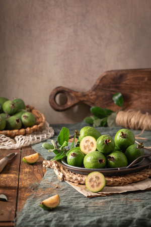 A rustic still life with ripe pineapple guavas, some cut open to reveal the fleshy pulp, on a small plate and in a basketの写真素材