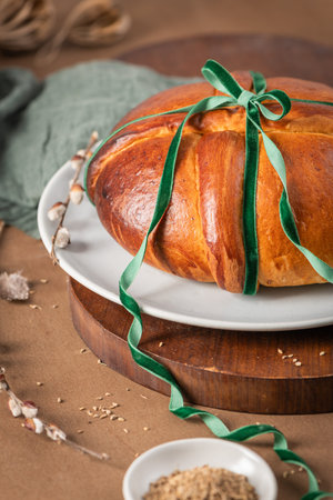 Portuguese traditional Easter cake Folar without eggs on easter table with a green velvet ribbon and...