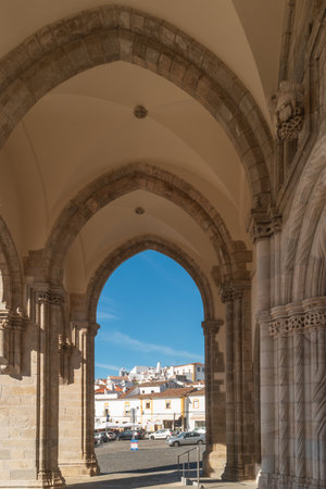 EVORA, Portugal - March 2, 2019. Framed view of historic Evora's whitewashed architecture through a centuries-old stone archway in Alentejoのeditorial素材