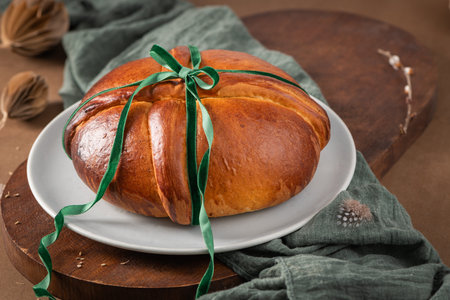 Portuguese traditional Easter cake Folar without eggs on easter table with a tied green ribbon