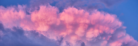 Colorful sky background with puffy clouds of pink and purple after summer rainstorm. Heaven at...