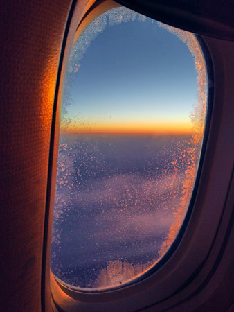 View from airplane window at orange and purple sunset. Golden hour. Travel and relax concept. Calm...