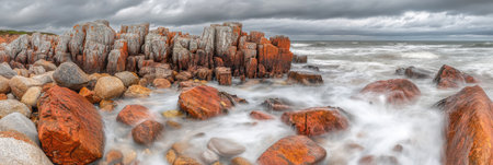 Dramatic Coastal Rocks Ocean Waves Red Orange Stones sea sky day view wild hard grey shot waterの素材