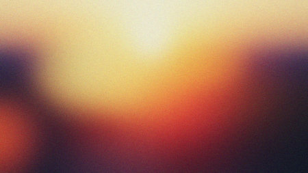 A vibrant abstract background featuring a gradient of warm colors transitioning from yellow to orange to dark red and black tones, creating a dynamic and artistic visual effect with soft blurred textureの素材