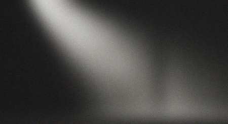 A dark grainy texture background with a dramatic light beam shining through, creating a mysterious and moody atmosphere, ideal for design projects and backgrounds.の素材
