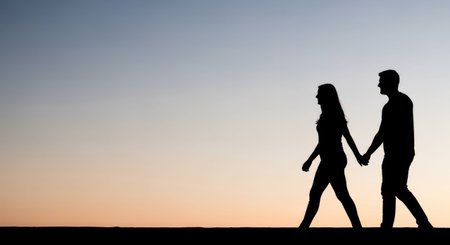 Silhouette of a man and woman holding hands on sunset backgroundの素材