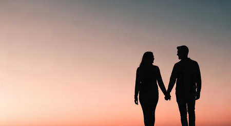 Silhouette of man and woman holding hands and looking at sunsetの素材