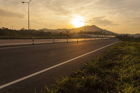 road crosses rural landscape with the silhouette of hill on background the colors of a sunsetの写真素材