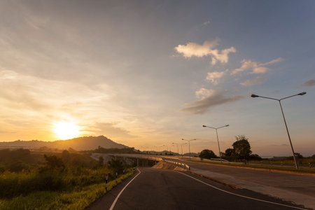 road crosses rural landscape with the silhouette of hill on background the colors of a sunsetの写真素材