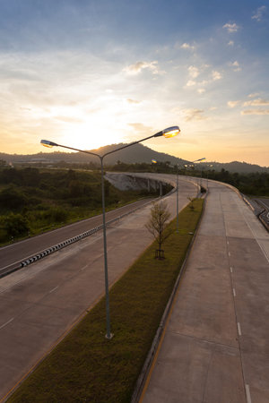 road crosses rural landscape with the silhouette of hill on background the colors of a sunset