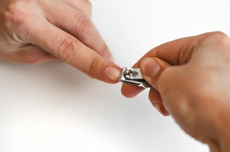 A young man does a manicure to himself. On white background. Hands. Stages of nail clipping. Close...