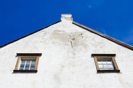 Old wooden Windows of the house. Side white facade of the house. Roof tiles. Bottom view. Estonia.の写真素材