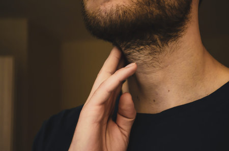 A young man checks his pulse. Keep your hand on your neck, determines the heart rhythm. Close up.