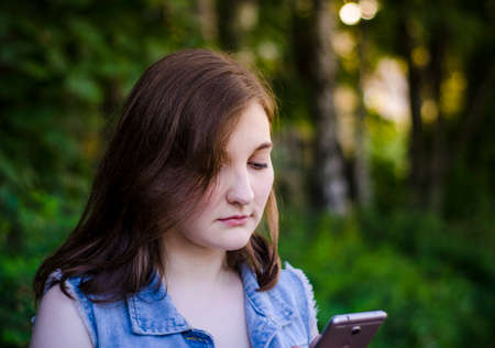 The girl waiting for an answer. I look at the phones, sad eyes. Expectation. Impatience. Brown hair with blue eyes. Photo.の写真素材