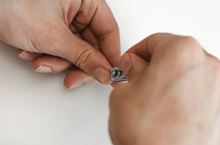 A young man does a manicure to himself. On white background. Hands. Stages of nail clipping. Close up.の写真素材