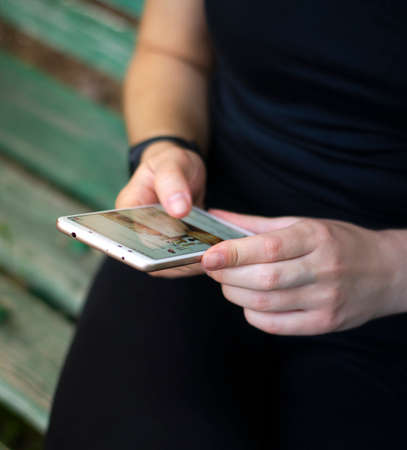 Girl leafing through a social network. Looks through the latest news and posts. Blonde woman in sports clothes. The view from the top. Photo.の写真素材