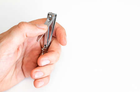 Young man holding a nail clipper tool. Manicures for men himself. On white background. Short fingernails. Hands. Close up.の写真素材