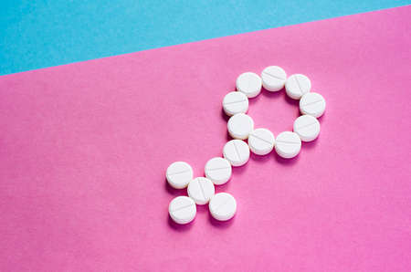 Sign of a woman from pills on a colored background. The concept of women's health and sexuality. Problems conceiving. Infertility treatment. Gender sign.の写真素材