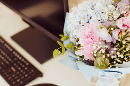 Donated flowers are on the desktop. Close up. Peonies, hydrangea and others. Soft focus. Monitor, keyboard, mouse, graphics tablet.の写真素材