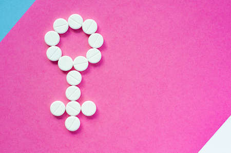 Sign of a woman from pills on a colored background. The concept of women's health and sexuality. Problems conceiving. Infertility treatment. Gender sign.の写真素材
