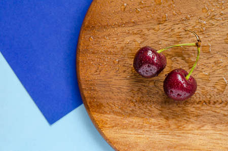 Ripe cherry, top view. On a wooden substrate on a blue background. Geometry. Summer berry. The concept of healthy eating.の写真素材
