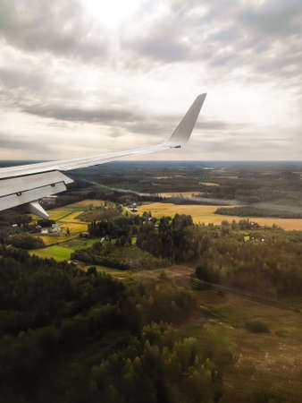 The view from the airplane window. The plane is landing. Visible land, forest, houses. Passenger photo.の写真素材