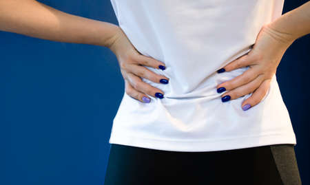 Pain in the kidneys. The concept of health. The girl is holding her back. Kidney disease, pyelonephritis, kidney stones, sand in the kidneys.の写真素材