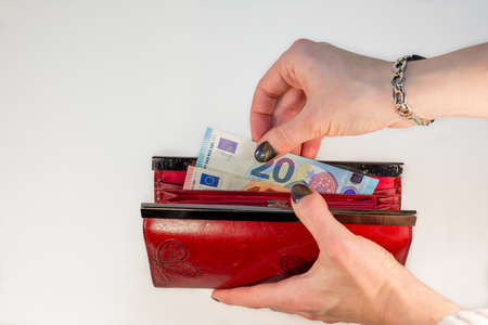 Abstract - woman hand holding red wallet and pulling out money - white backgroundの写真素材