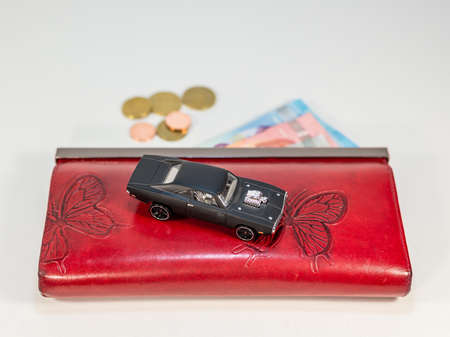 Abstract - luxury car on the red wallet with money - expensive toy for rich womanの写真素材