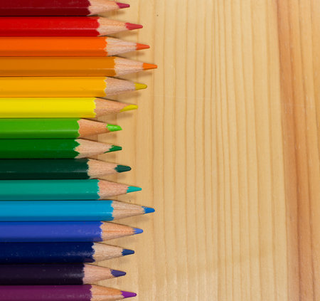 Row of colorful pencils rainbow order on wooden table