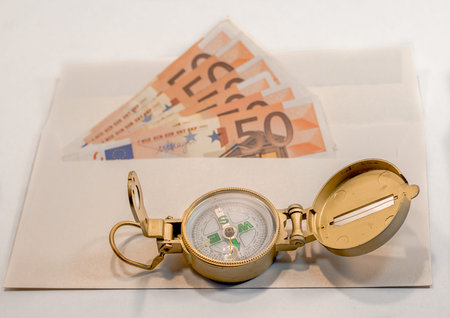 Abstract composition - a lot of money in the envelope and compass for travel