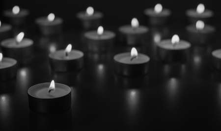 Flame of many candles burning on the background in black and white colorの写真素材
