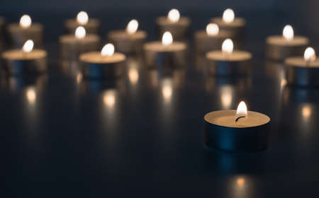 Flame of many candles burning on the background in blue and yellow colorの写真素材
