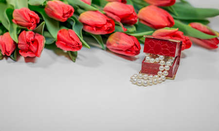 Red spring tulips with small box with pearls - romantic present for woman on white backgroundの写真素材