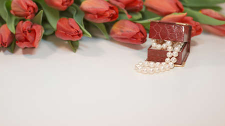 Red spring tulips with small box with pearls - romantic present for woman on white backgroundの写真素材
