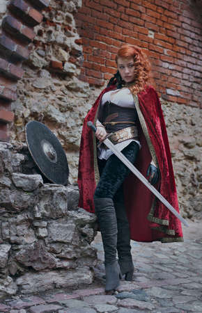Warrior woman with sword in medieval clothes on the street is very dangerousの写真素材