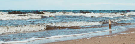 Wooden stick standing against the waves of north sea on the beach - nature landscapeの写真素材