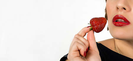 Red woman lips and hand with strawberry eaing dessertの写真素材
