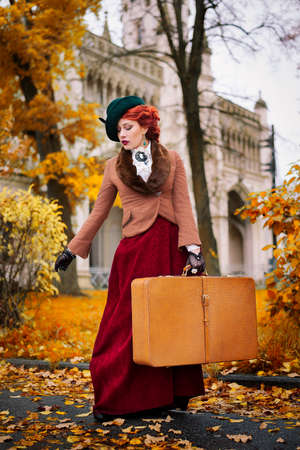 Beautiful woman face in the hat and red hair with luggage autumn travel - countess voyageの写真素材