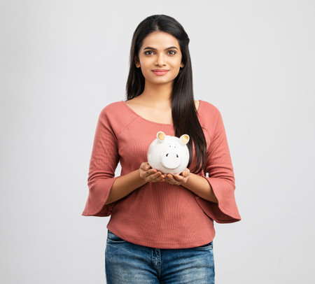 happy asian woman with piggy bank over gray background. pension savingsの写真素材