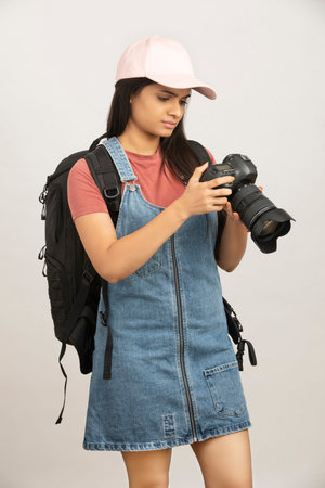 Young woman with camera and backpack on white background. Space for text
