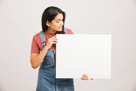 Young woman in apron holding white blank board on white background.の写真素材