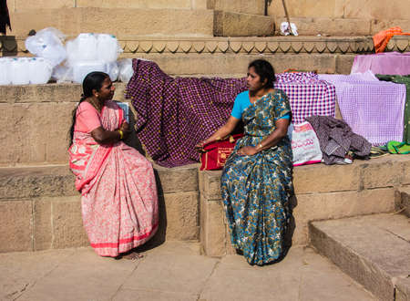 Two women are sitting on the holy ghats of the ancient hindu city of Varanasi, and talkingのeditorial素材
